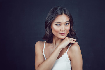 Portrait of a beautiful asian woman with makeup and light curls on black background.