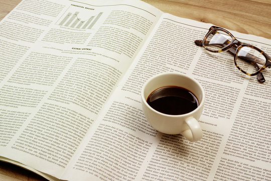 Newspaper on wooden table with coffee and eyeglasses. Vintage effect style pictures.