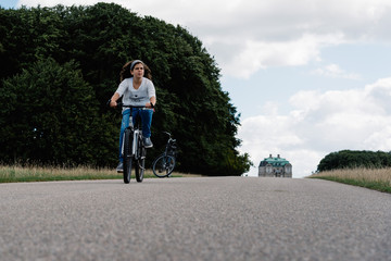 Pretty young woman riding bike in a country road in the park