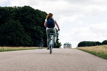 Fototapeta premium Pretty young woman riding bike in a country road in the park