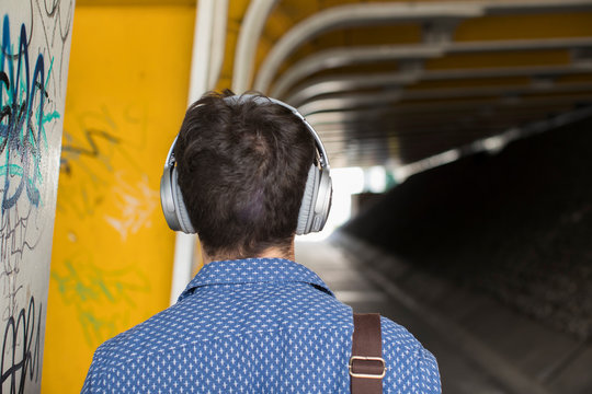 Rear View Of Man In Urban Setting Wearing Headphones