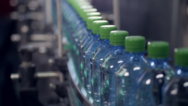 A slow moving conveyor with PET bottles ready for labeling. 