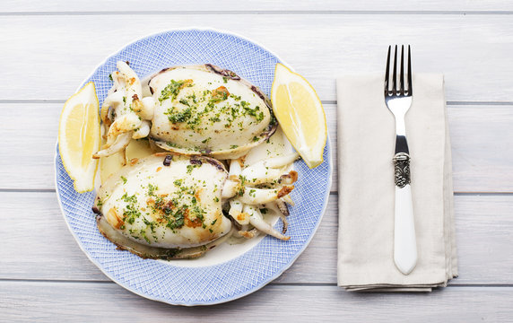 Top view of cuttlefish with hajo, parsley and lemon next to fork and napkin. Food.