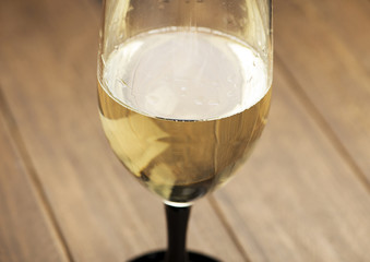 Glass of white wine on wooden table.