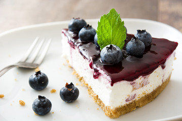Piece of blueberry cheesecake on wooden table
