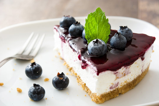 Piece of blueberry cheesecake on wooden table
