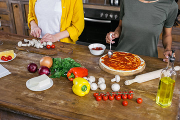 Cropped shot of young women cooking pizza together in kitchen