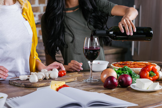 Cropped Shot Of Women Drinking Wine While Cooking Pizza Together