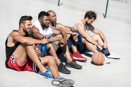 Side View Of Multicultural Basketball Team Resting After Game On Court