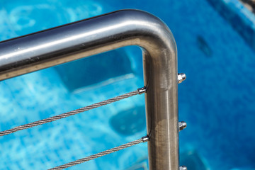 detail of thermal swimming pool tiled stairs down water and metal handle