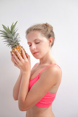 Portrait of a pretty young summer girl holding pineapple isolated over  background. Concept of a healthy lifestyle.