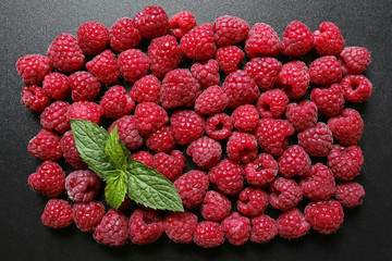 fresh raspberries with mint leaf on black background