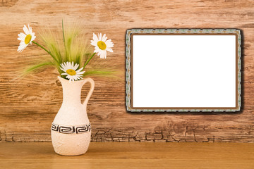 Mocap, a blank white screen with beige plastic frame on bright wall and ceramic vase with daisies on a wooden table, mock up
