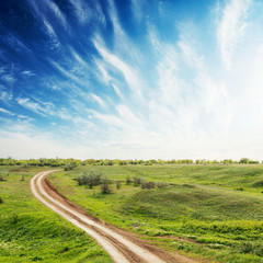 Fototapeta na wymiar road in green meadow and sunset in deep blue sky