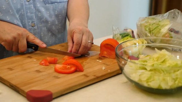 Close up of a woman cutting tomatoes for a salad