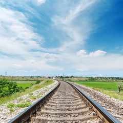 Fototapeta premium railway to horizon in green landscape under white clouds