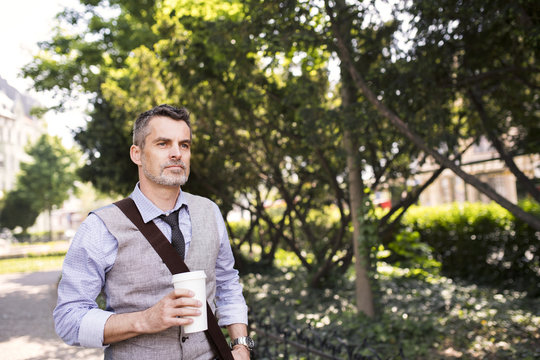 Mature businessman with coffee in city park