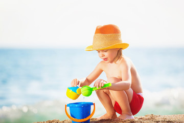 Happy child is playing with toys at sea shore background.