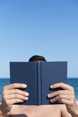 man reading a book on the beach