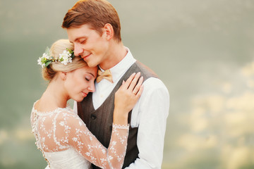 Close-up portrait of a wedding couple against the background of the water at sunset sun