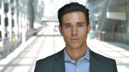 Portrait of a young handsome businessman (student) in a suit, smiling, successful happy, at the station, at the airport. Concept: new business, travel the world, communication, contacts, business deal