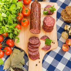 Sliced salami with cherry tomatoes and spices on table