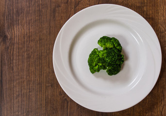 broccoli on white plate on the brown wooden table background. with copy space. top view.