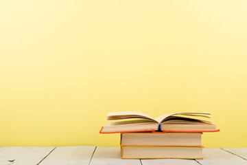 education and wisdom concept - open book on wooden table, color background