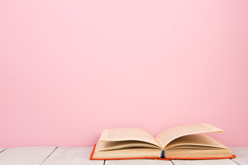 education and wisdom concept - open book on wooden table, color background