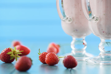 Strawberry milk cocktail in Irish mugs and fresh strawberries on light blue table