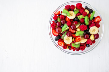 Tasty fresh fruit salad on white wooden background. Top view. Natural food
