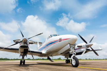 Small Airplane Parked at Airport with beautiful blue sky white clouds background - obrazy, fototapety, plakaty