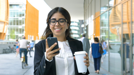 Portrait of a young beautiful business woman (student) in a suit, glasses, walking around the city, drinking coffee, talking on the phone. Concept: new business, communication, Arab, banker, manager.