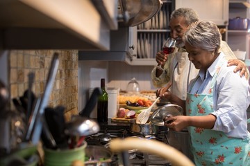 Man having wine while woman preparing food