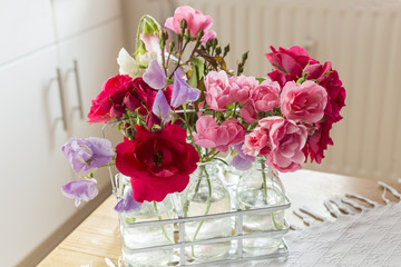 Wicken und Rosen in Gläsern