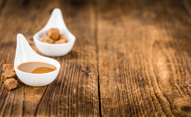 Portion of Caramel Sauce on wooden background (selective focus)