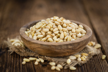 Portion of Pine Nuts on wooden background (selective focus)