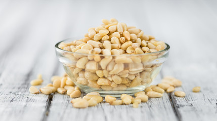 Portion of Pine Nuts on wooden background (selective focus)