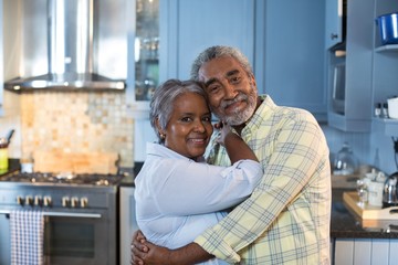 Portrait of couple embracing while standing in kitchen
