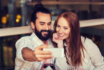 couple taking selfie by smartphone at restaurant