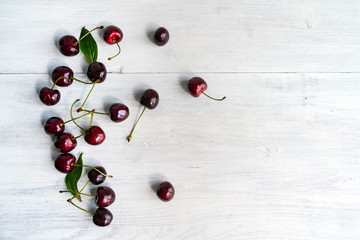 Fototapeta na wymiar Summer food background - ripe cherry berries on white wooden table. Copy space.