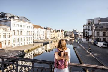 Fototapeta na wymiar Woman enjoying great view on the water channel standing back on the bridge in Gent city in Belgium