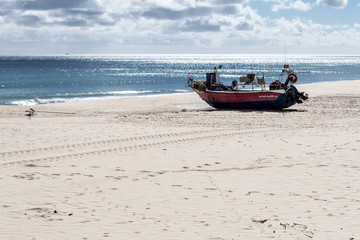 Naklejka premium Stranded boat in the beach of Salema (Algarve, Portugal)