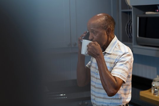 Man Having Coffee While Talking On Phone 