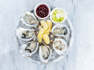 Fresh oysters platter with sauce and lemon