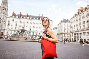 Young woman tourist with photo camera and red bag walking on the Royal main square in Nantes city, France