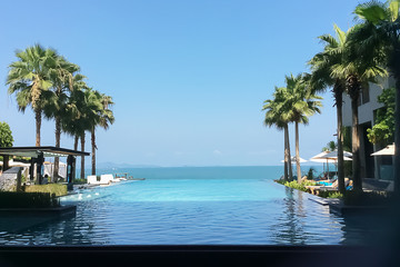 Perspective view of outdoors dramatic infinity swimming pool to the ocean on beautiful morning in summer.