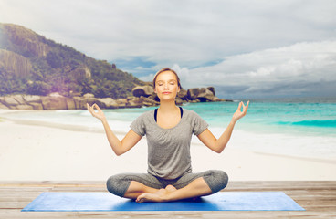 woman doing yoga meditation in lotus pose on beach