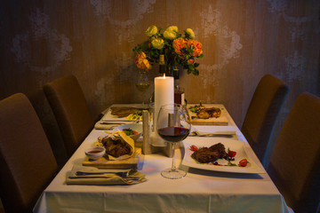 Served table with dishes from meat, chicken and fish with wine and whiskey. Romantic dinner in the restaurant by candlelight