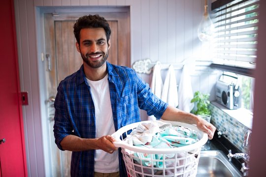 Portrait Of Smiling Young Man Holding Laundry Basket